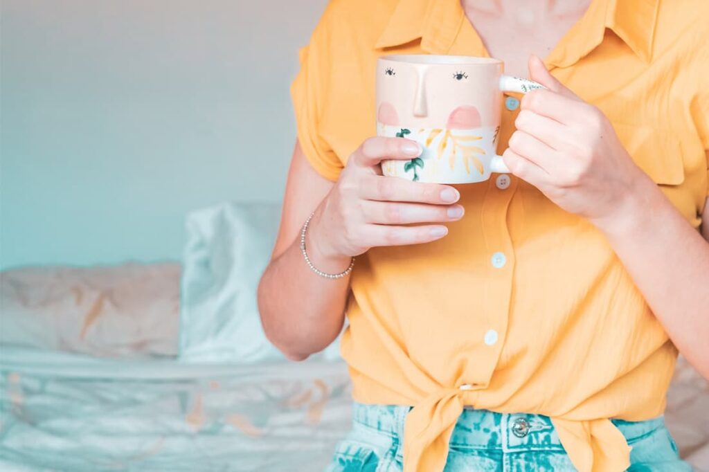 Person holding a decorative mug, illustrating a calm and relaxed approach to managing finances.
