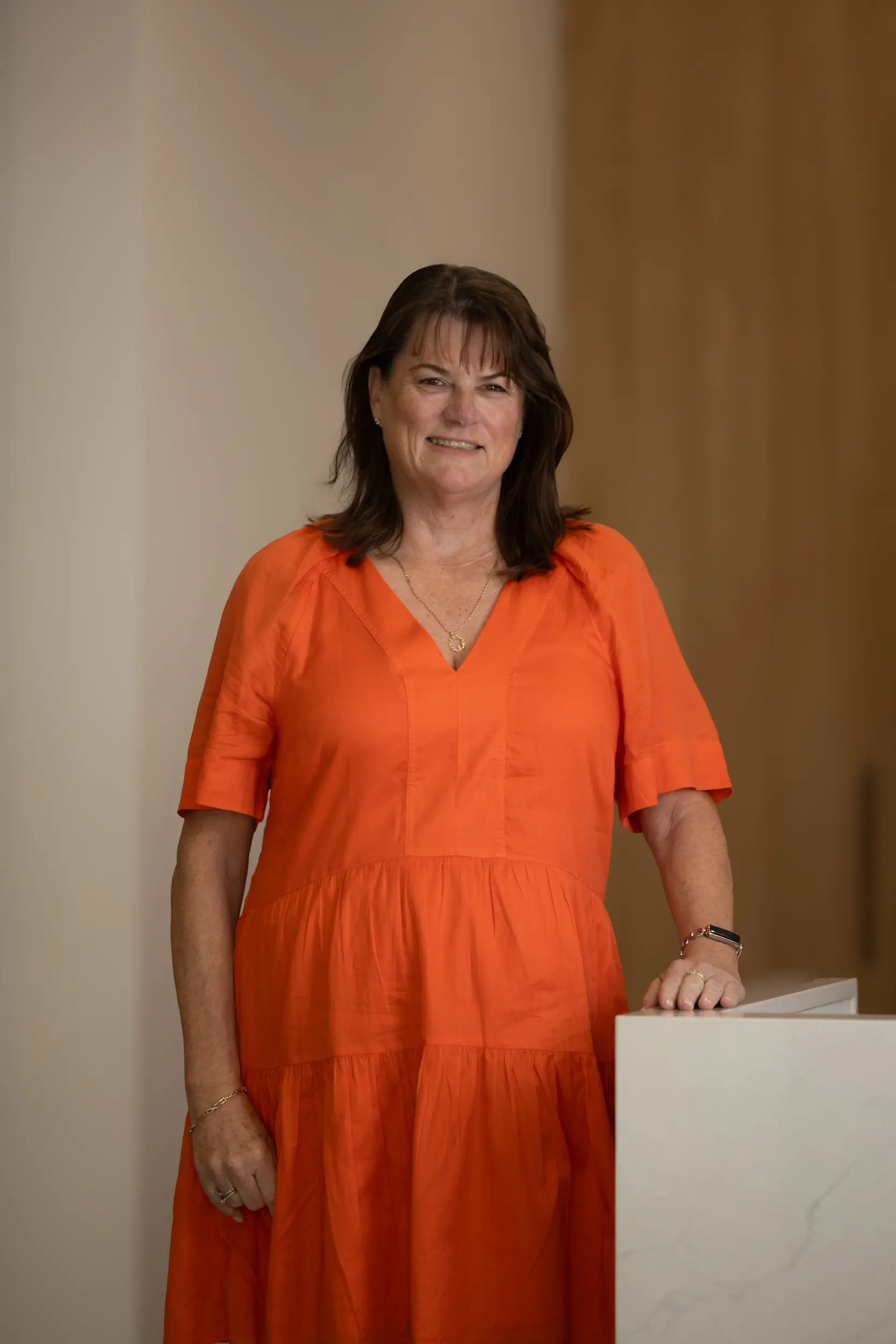 Lenore McKinniery, senior associate at FirstPoint Mortgage Brokers, smiling in a bright orange dress.