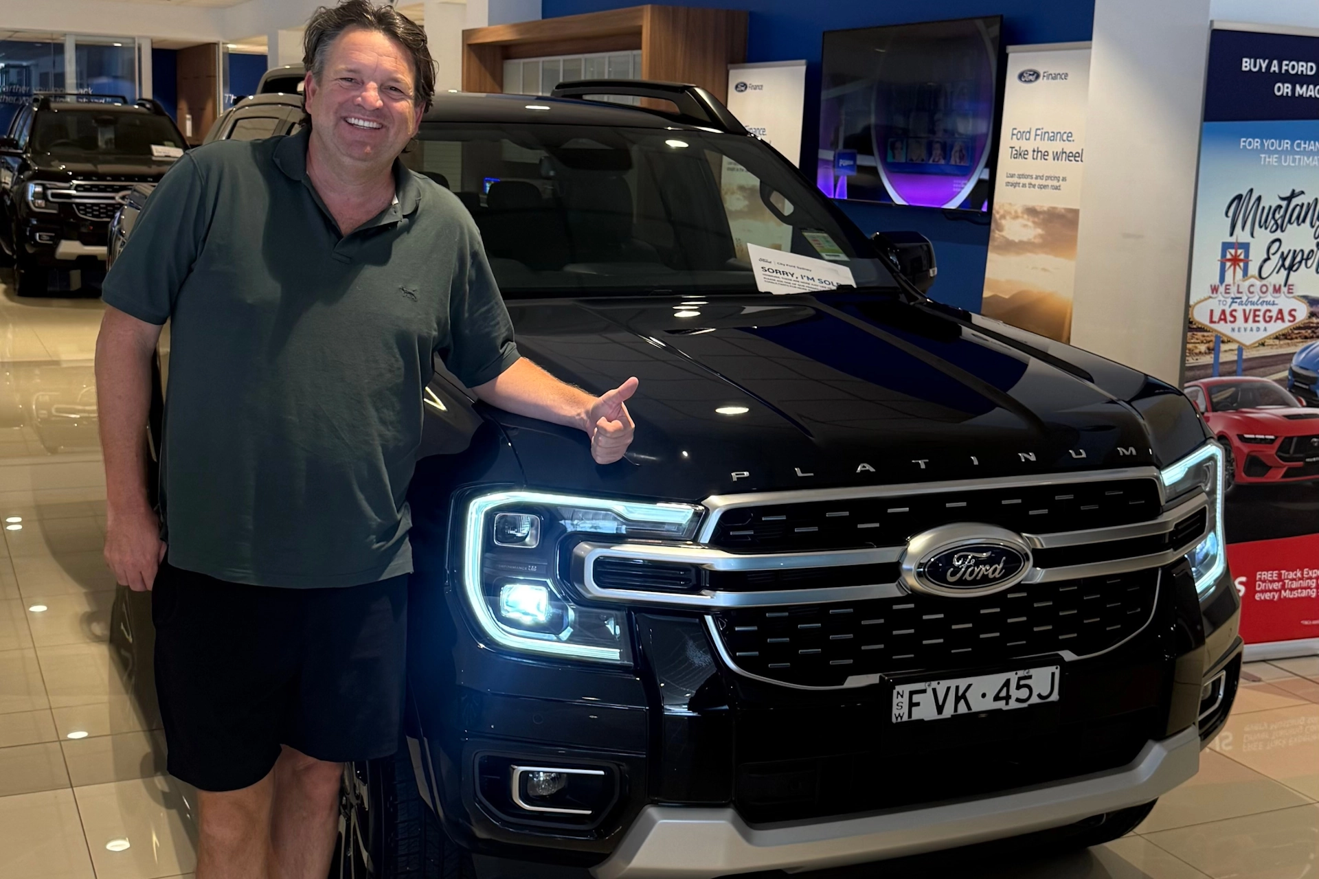 Man smiling and giving a thumbs-up next to a new Ford Ranger platinum in a