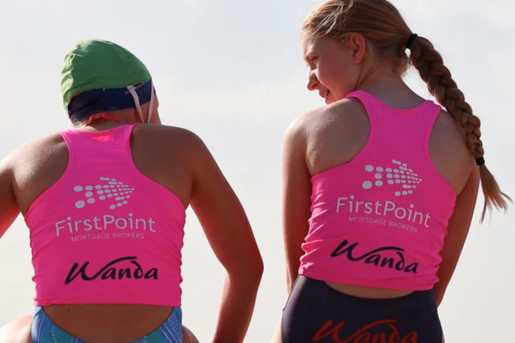 Two athletes wearing FirstPoint Mortgage Brokers branded swimwear during a Wanda triathlon event in Australia.