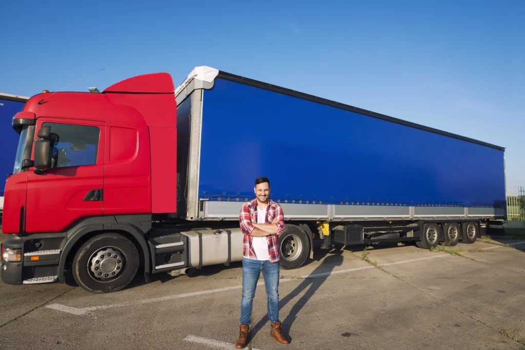 Truck driver standing in front of a red and blue semi-trailer truck in Australia.